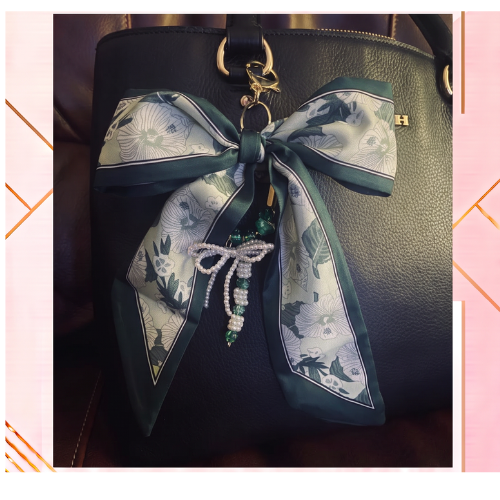 Gray floral bow bag charm with dark trim, coquette pearl bow, glass beads, and pearl bar.